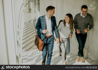 Group of corporate business professionals climbing at stairs in office corridor on a sunny day