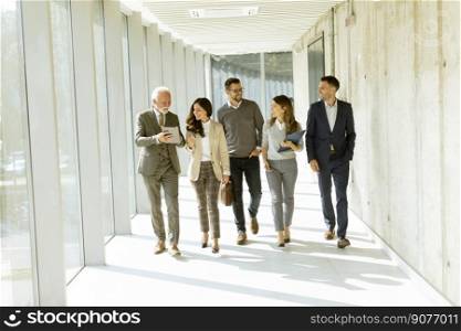 Group of corporate business professionals walking through office corridor on a sunny day