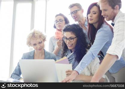 Group of creative businesspeople using laptop in office