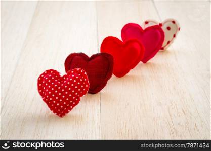 Group of cute red tone hearts handmade crafts from cotton and silk cloth stack on wood background, love and valentine&rsquo;s day symbol