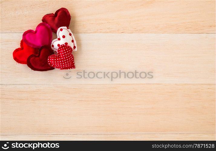 Group of cute red tone hearts handmade crafts from cotton and silk cloth place at conner of wood background, love and valentine symbol