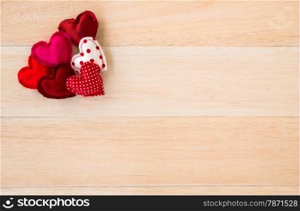 Group of cute red tone hearts handmade crafts from cotton and silk cloth place at conner of wood background, love and valentine symbol