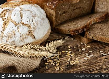Group of dark breads with wheat, sunflower and rye grains on a wooden vintage table.