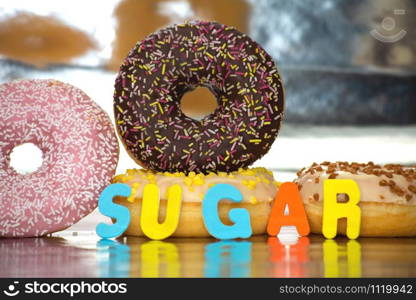 Group of delicious colorful glazed donuts near colorful background with the word sugar sweet candy concept. Group of delicious colorful glazed donuts near colorful background with the word sugar