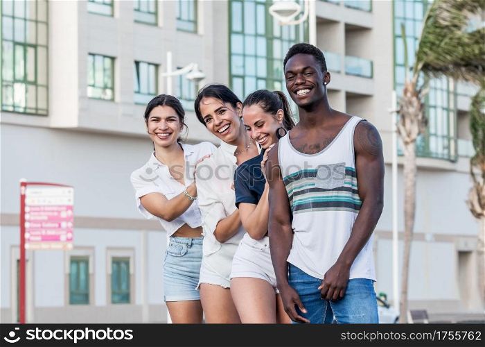 Group of diverse friendly people standing in city and enjoying weekend together on Lanzarote while smiling and looking at camera. Company of multiethnic friends looking at camera in city