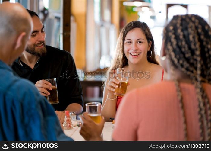 Group of diverse friends drinking beer while enjoying a meal together in a restaurant. Friends concept.