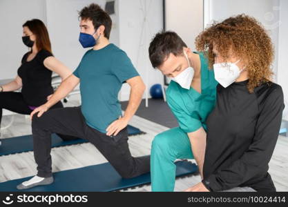 Group of doctor and patients in a rehab center wearing facemasks while doing their physiotherapy. High quality photo. Group of doctor and patients in a rehab center wearing facemasks while doing their physiotherapy.