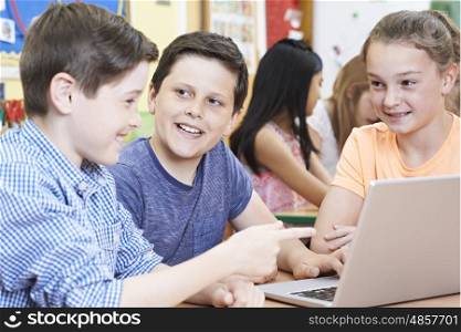 Group Of Elementary School Children Working Together In Computer Class