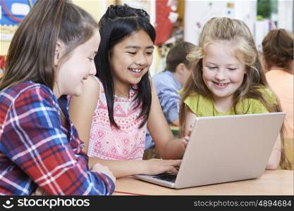 Group Of Elementary School Children Working Together In Computer Class