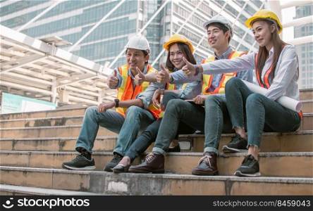 Group of engineer wearing safety helmets, making thump up and discussing about their construction project outside