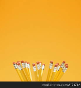 Group of eraser ends of pencils on orange background.