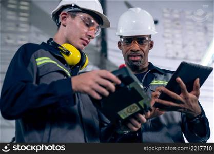 Group of factory job workers using adept machine equipment in a workshop . Industry manufacturing and engineering technology concept .. Group of factory job workers using adept machine equipment in a workshop