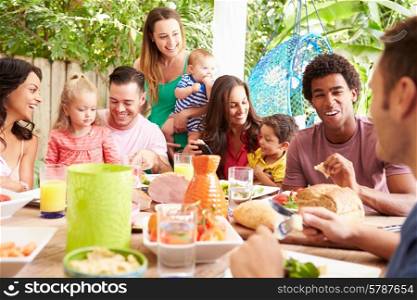 Group Of Families Enjoying Outdoor Meal At Home