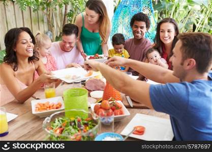 Group Of Families Enjoying Outdoor Meal At Home