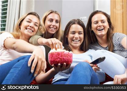 Group Of Female Teenage Friends Watching Television At Home