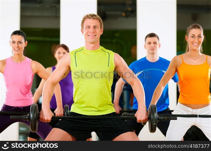 Group of five people exercising using barbells in gym or fitness club to gain strength and fitness