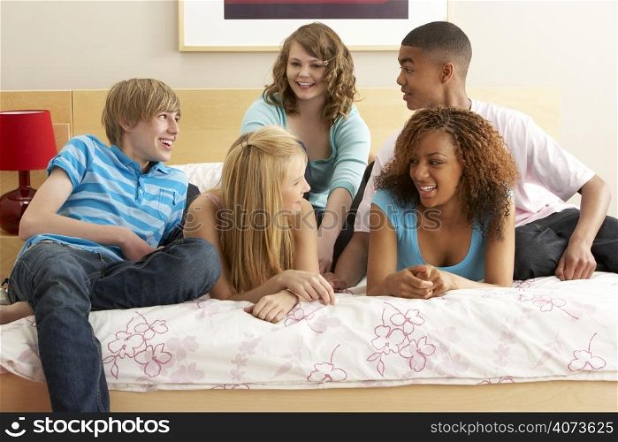 Group Of Five Teenage Friends Hanging Out In Bedroom