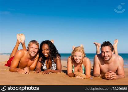 Group of Four friends - men and women - on the beach having lots of fun in their vacation