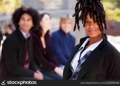 Group of four people of different ethnicities with one woman as focus of image. Horizontally framed shot.