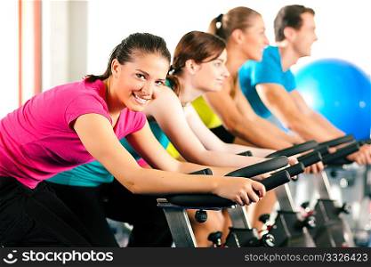 Group of four people spinning in the gym, exercising their legs doing cardio training