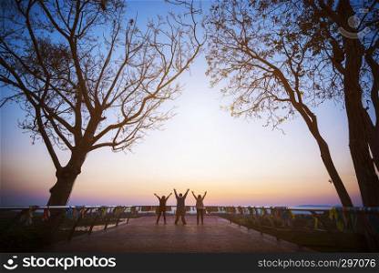 Group of four people stands on the top of mountain in winner pose. Team or teamwork success concept.Space for text. Travel concept.