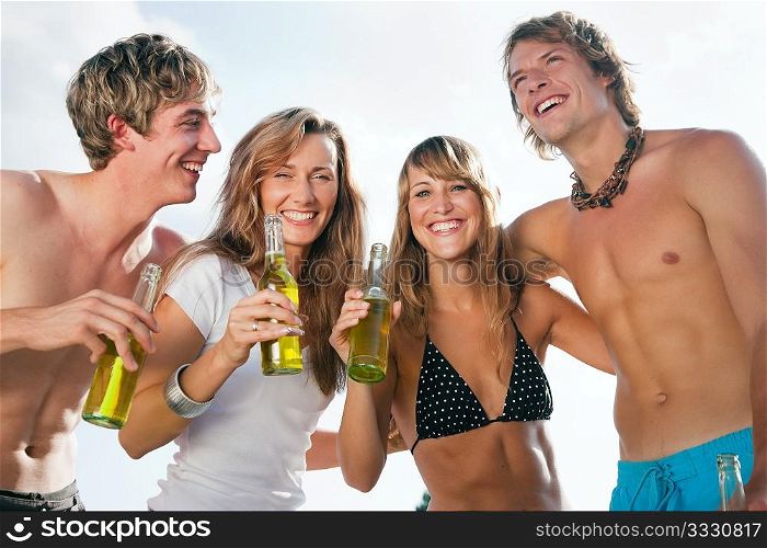 Group of four very beautiful people celebrating hot party on the beach in the summer of their lives - focus on faces