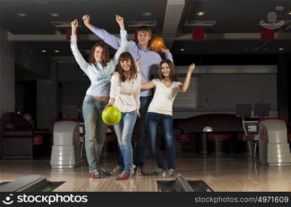 Group of four young smiling people playing bowling. Weekend with friends