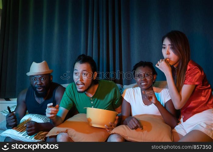 Group of friend sitting on sofa for watching television together, feeling exciting for winning game emotional in the night light environment background at home