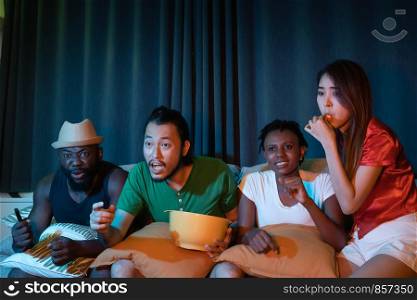 Group of friend sitting on sofa for watching television together, feeling exciting for winning game emotional in the night light environment background at home