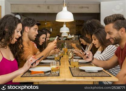 Group of friends at a restaurant with all people on the table occupied with cellphones