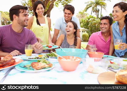 Group Of Friends Celebrating Enjoying Meal In Garden At Home