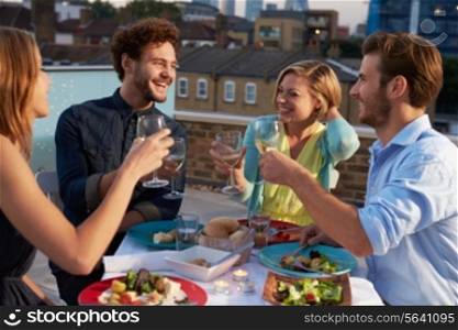 Group Of Friends Eating Meal On Rooftop Terrace
