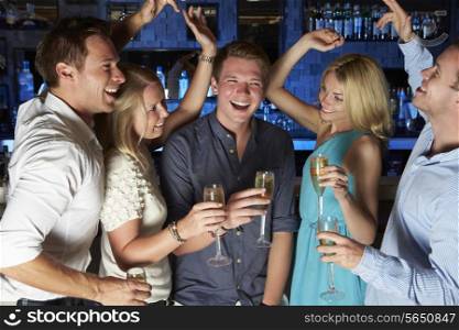 Group Of Friends Enjoying Glass Of Champagne In Bar