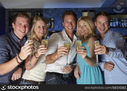 Group Of Friends Enjoying Glass Of Champagne In Bar