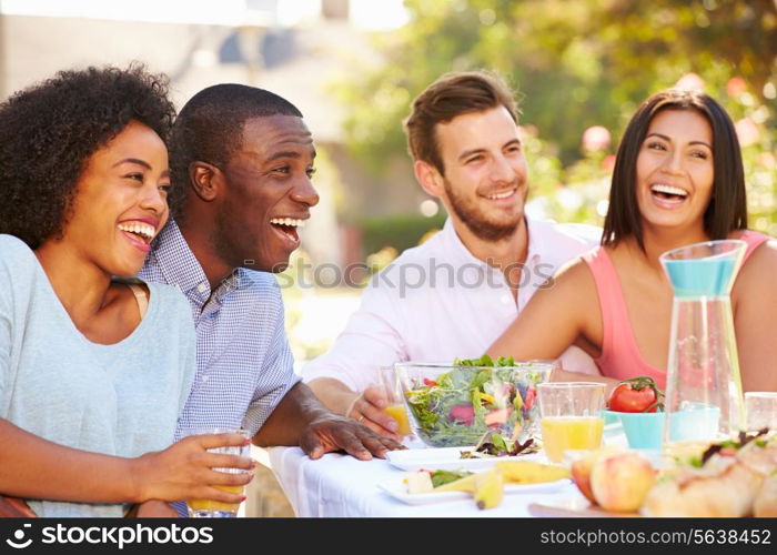 Group Of Friends Enjoying Meal At Outdoor Party In Back Yard