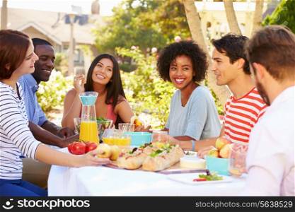 Group Of Friends Enjoying Meal At Outdoor Party In Back Yard