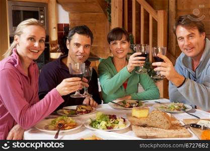 Group Of Friends Enjoying Meal In Alpine Chalet Together