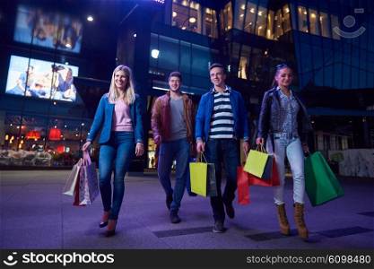 Group Of Friends Enjoying Shopping Trip Together&#xA;group of happy young frineds enjoying shopping night and walking on steet on night in with mall in background