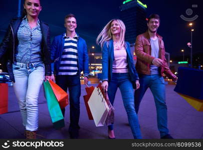 Group Of Friends Enjoying Shopping Trip Together&#xA;group of happy young frineds enjoying shopping night and walking on steet on night in with mall in background