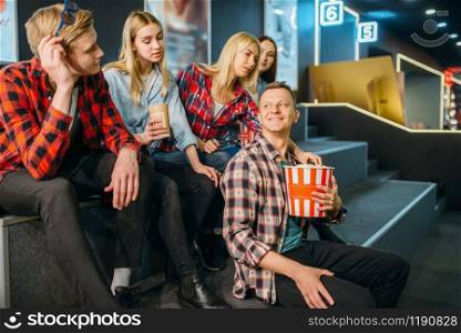 Group of friends having fun in cinema hall before the showtime. Male and female youth waiting in movie theater