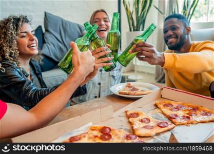 Group of friends having fun while eating pizza and drinking beer together. Friends concept.