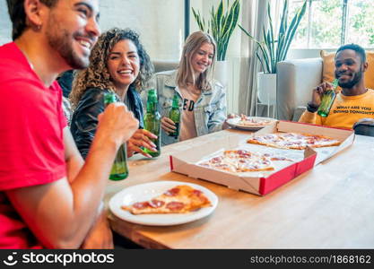 Group of friends having fun while eating pizza and drinking beer together. Friends concept.