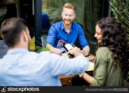 Group of friends having outdoor garden party and drinking red wine