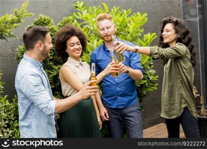 Group of friends having outdoor garden party toast with alcoholic cider drinks