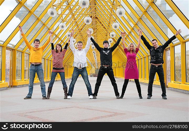 group of friends it stand taking hands and rising them on footbridge