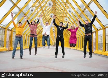 group of friends jump on footbridge taking as hands