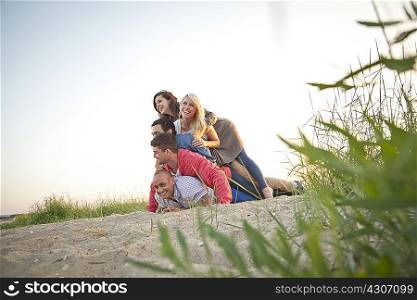 Group of friends making human pile on beach