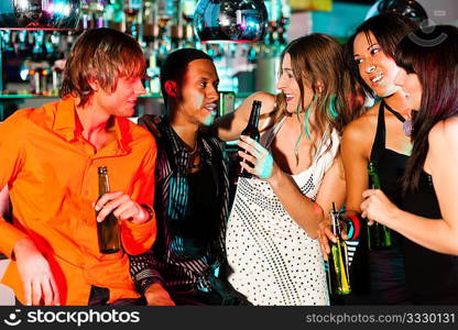 Group of friends - men and women of different ethnicity - having fun in a disco or nightclub