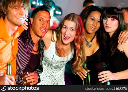 Group of friends - men and women of different ethnicity - having fun in a disco or nightclub