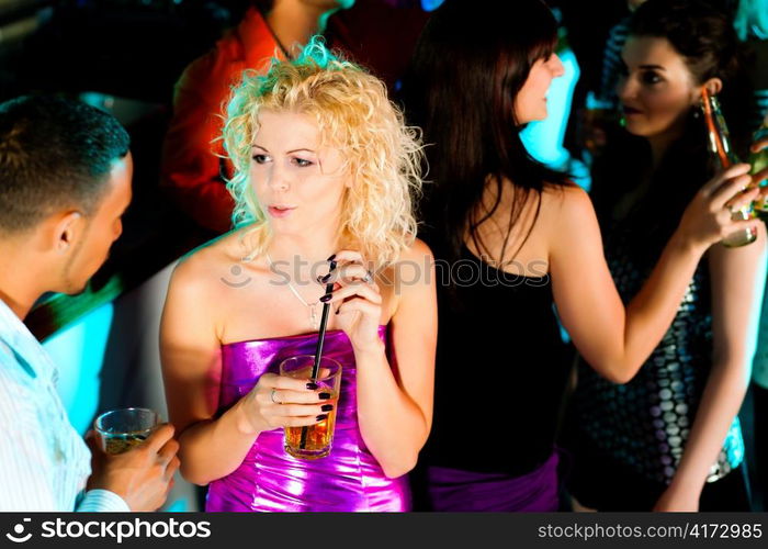 Group of friends - men and women of different ethnicity - having fun in a disco or nightclub